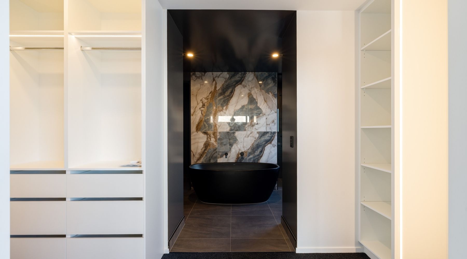Hallmark Homes ensuite with a black freestanding bath, marble tile feature wall, and dark ceilings — modern Christchurch build.