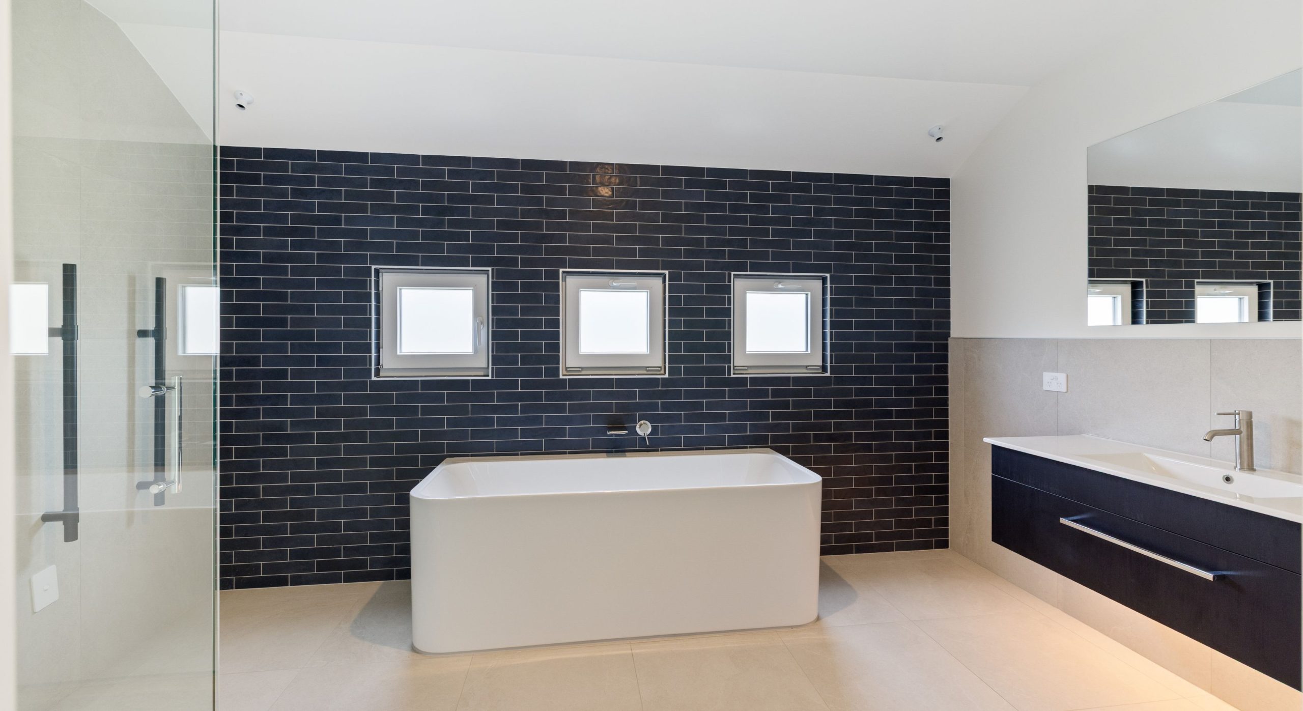 navy tiled feature wall with free standing bath