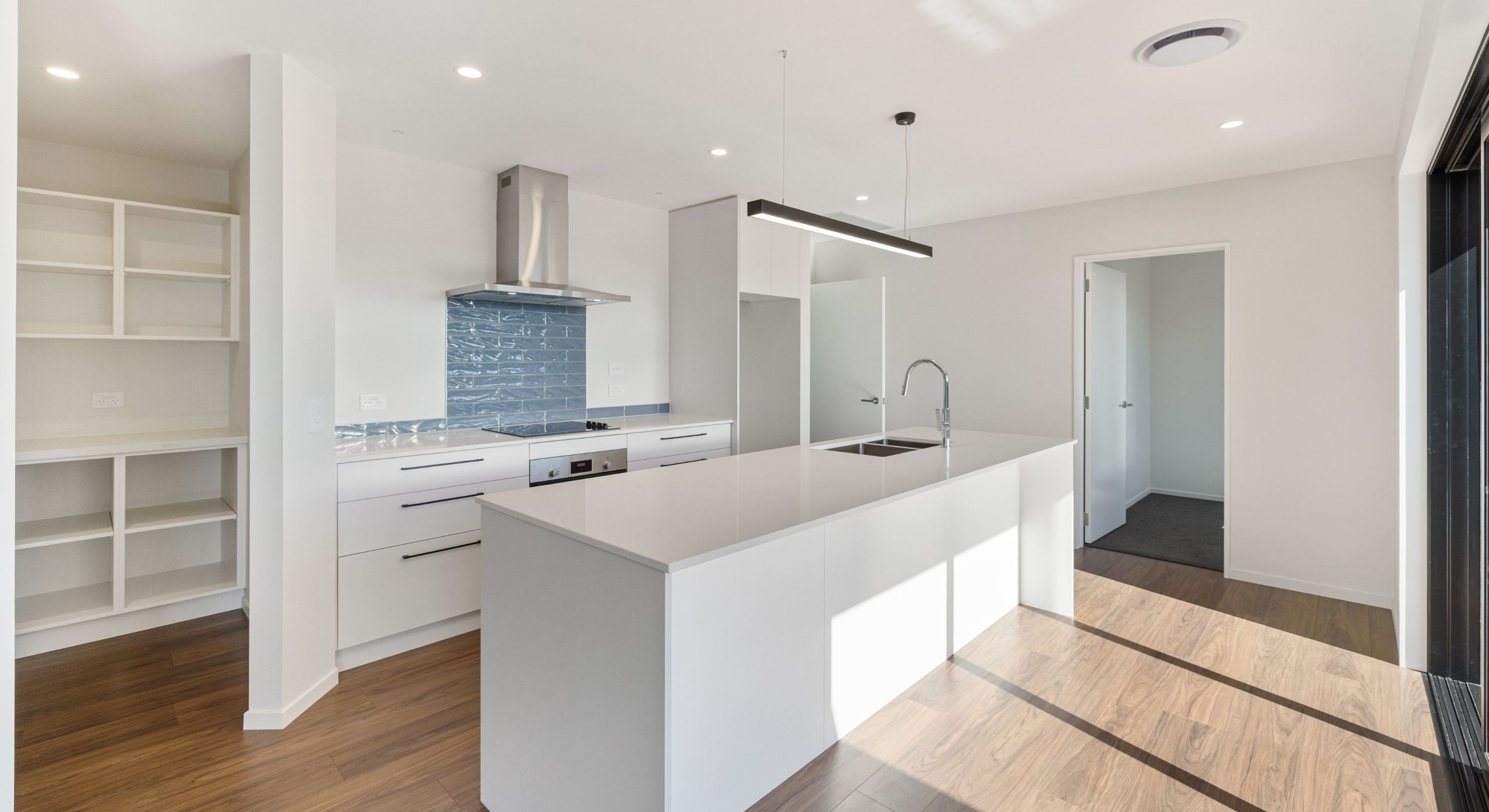 Sleek modern all white kitchen with feature blue backsplash