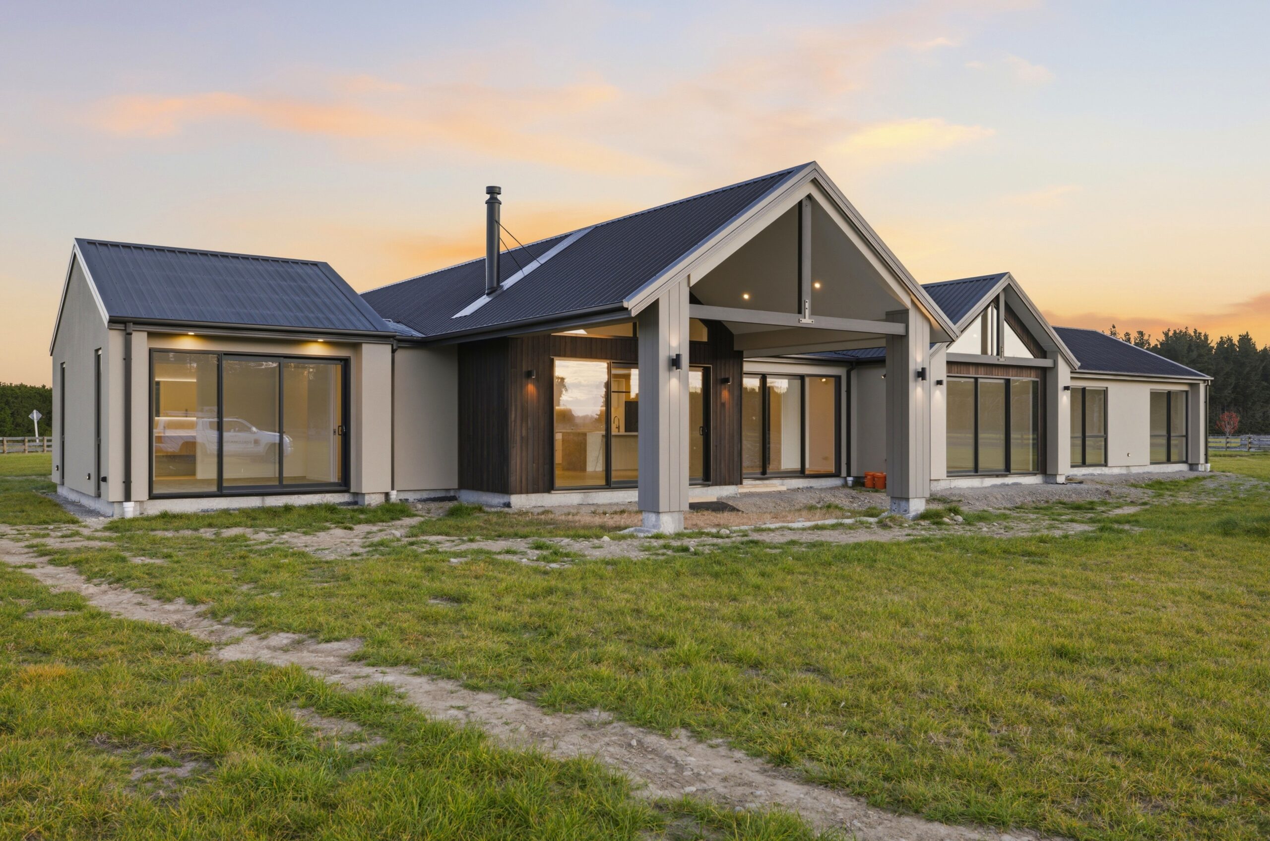 Wanaka plan, Hallmark Homes West Melton. Side gable wing lit up at dusk, pitched roofline against a fading sky.
