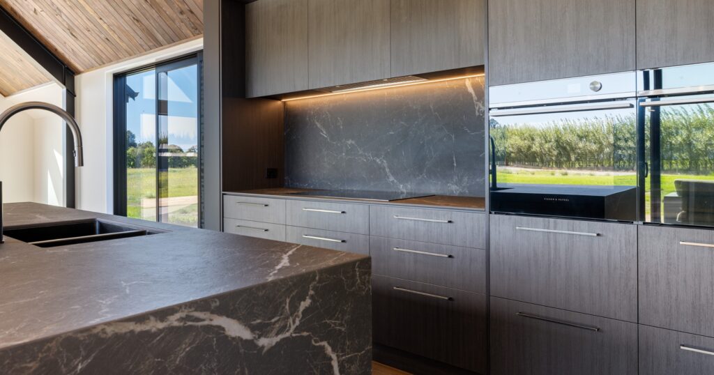 Dark natural stone kitchen benchtop with soft veining, a statement stone kitchen trend in a Canterbury new build