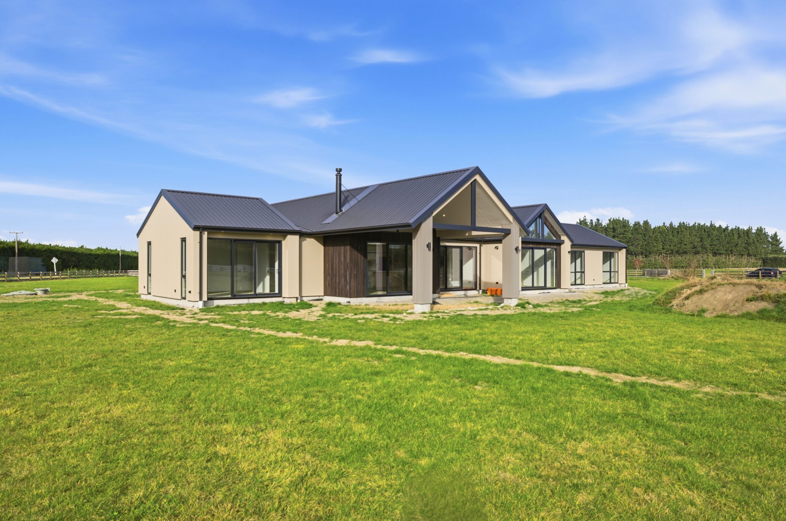 Wanaka plan, Hallmark Homes West Melton. Gravel driveway leading to the home, set on a grassed rural section.