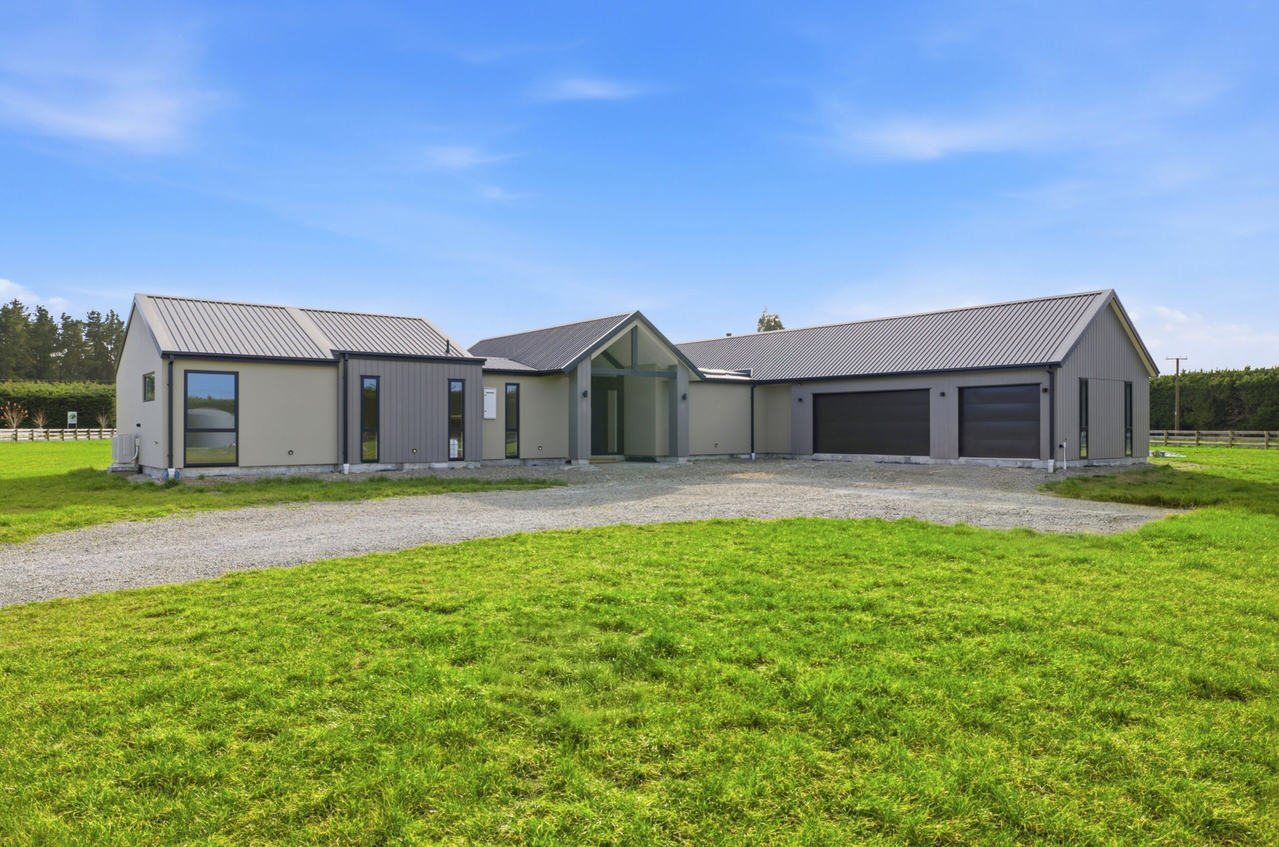 Wanaka plan, Hallmark Homes West Melton. Full front elevation under a clear blue sky, showing the gabled rooflines and triple garage.