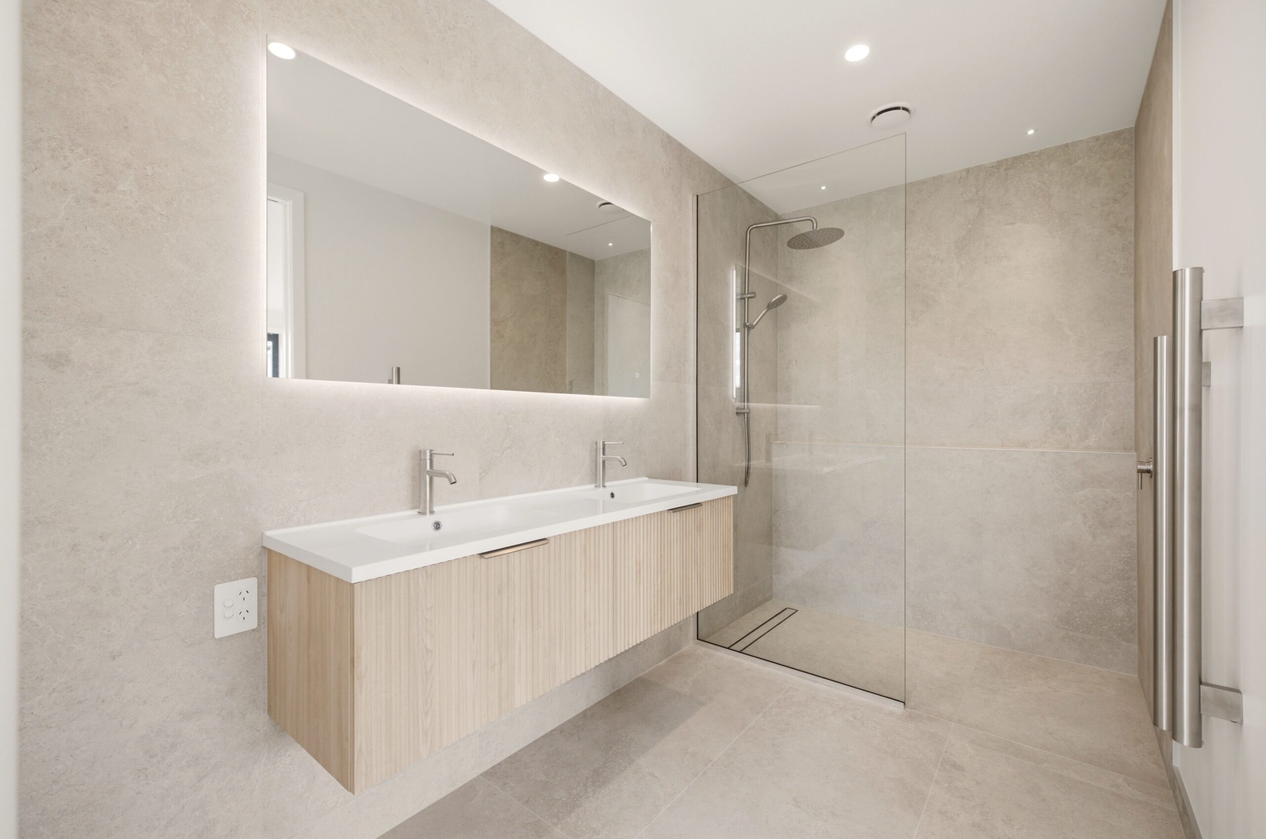Wanaka plan, Hallmark Homes West Melton. Floating timber slat vanity with double basins and a full width backlit mirror.